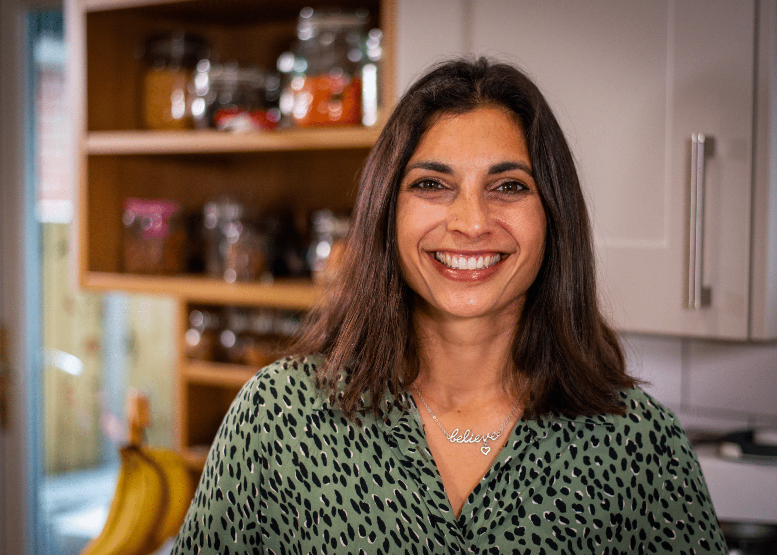 Image of Priya Tew, eating disorder dietitian in her kitchen in a green dress